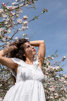 Spring concept. Nature.Young caucasian woman enjoying the flowering of an apple trees, walking in spring apple gardens