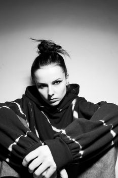 beautiful brunette girl in a black hoodie, light background. High quality photo