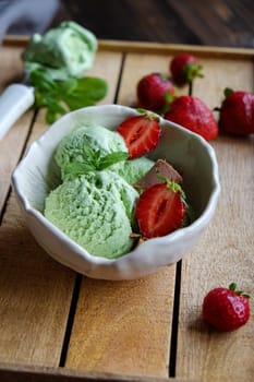 Pistachio Ice Cream in a white bowl with strawbeeries