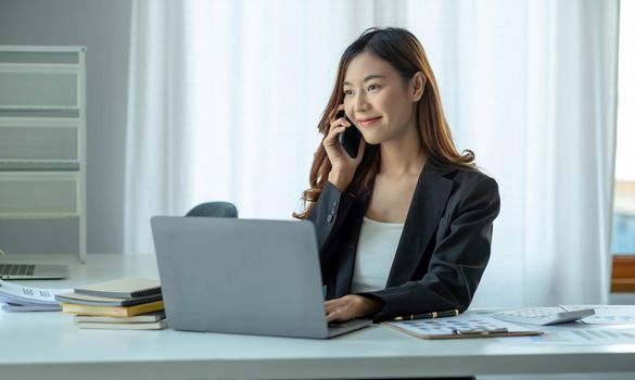 Asian business woman have the joy of talking on the phone, laptop and tablet on the office desk..