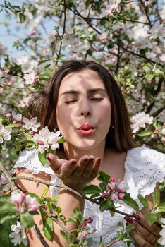 Spring concept. Nature.Young caucasian woman enjoying the flowering of an apple trees, walking in spring apple gardens