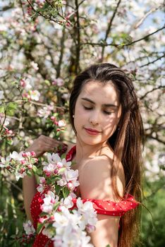 Spring concept. Nature.Young caucasian woman enjoying the flowering of an apple trees, walking in spring apple gardens