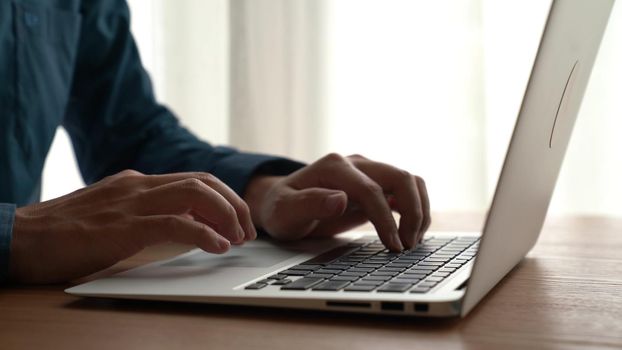 Businessman hand work on capable laptop computer at office table close up shot and selective focus at middle section of laptop computer keyboard while typing and working