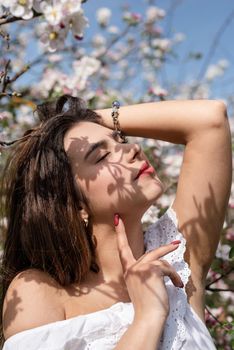 Spring concept. Nature.Young caucasian woman enjoying the flowering of an apple trees, walking in spring apple gardens