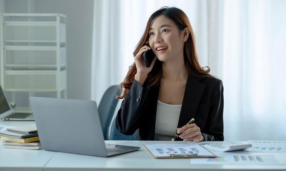 Asian business woman have the joy of talking on the phone, laptop and tablet on the office desk..