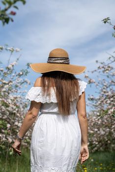 Spring concept. Nature.Young caucasian woman enjoying the flowering of an apple trees, walking in spring apple gardens