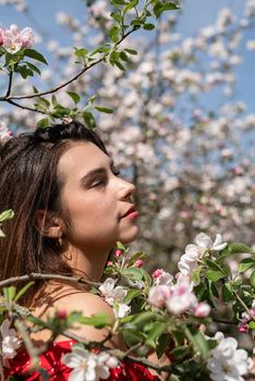 Spring concept. Nature.Young caucasian woman enjoying the flowering of an apple trees, walking in spring apple gardens