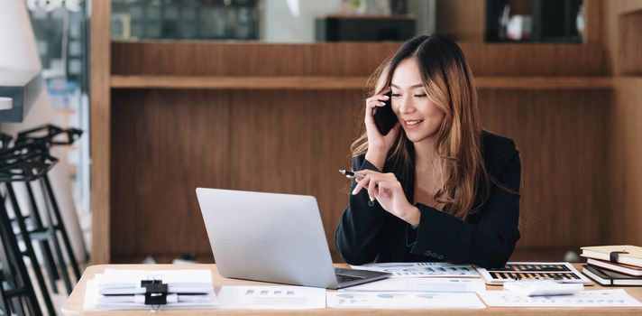 Asian business woman have the joy of talking on the phone, laptop and tablet on the office desk..