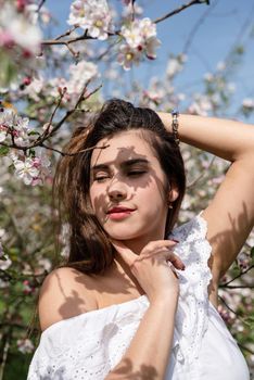 Spring concept. Nature.Young caucasian woman enjoying the flowering of an apple trees, walking in spring apple gardens. Shadow overlay on face