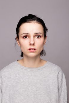 emotional woman in a gray sweatshirt, gray background. High quality photo