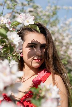 Spring concept. Nature.Young caucasian woman in red dress and summer hat enjoying the flowering of an apple trees, walking in spring apple gardens