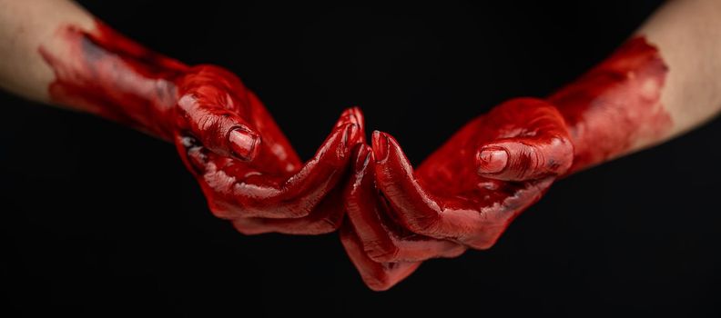 Women's hands in blood on a black background