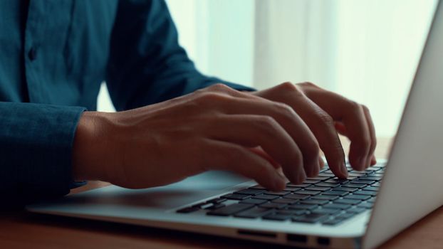 Businessman hand work on capable laptop computer at office table close up shot and selective focus at middle section of laptop computer keyboard while typing and working