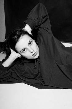 a woman in a black hoodie lies on the floor, black and white photography. High quality photo