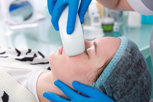 Young woman receiving electric galvanic anti-aging face spa massage at beauty salon. Galvanic massage helps to speed up metabolism, improve regeneration and restore skin protection from harmful external factors.