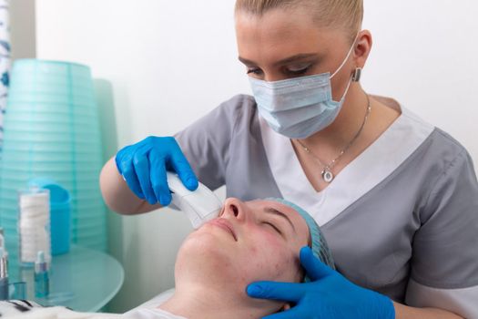 Young woman receiving electric galvanic anti-aging face spa massage at beauty salon. Galvanic massage helps to speed up metabolism, improve regeneration and restore skin protection from harmful external factors.