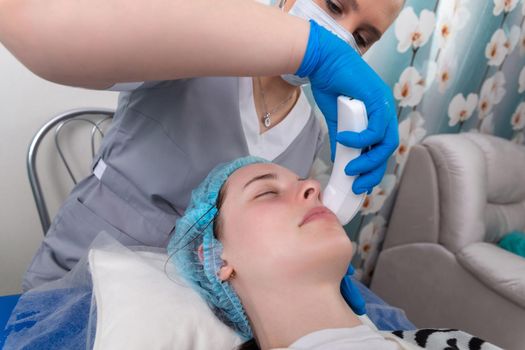 Young woman receiving electric galvanic anti-aging face spa massage at beauty salon. Galvanic massage helps to speed up metabolism, improve regeneration and restore skin protection from harmful external factors.