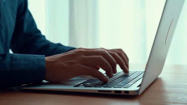 Businessman hand work on capable laptop computer at office table close up shot and selective focus at middle section of laptop computer keyboard while typing and working