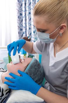 Young woman receiving electric galvanic anti-aging face spa massage at beauty salon. Galvanic massage helps to speed up metabolism, improve regeneration and restore skin protection from harmful external factors.