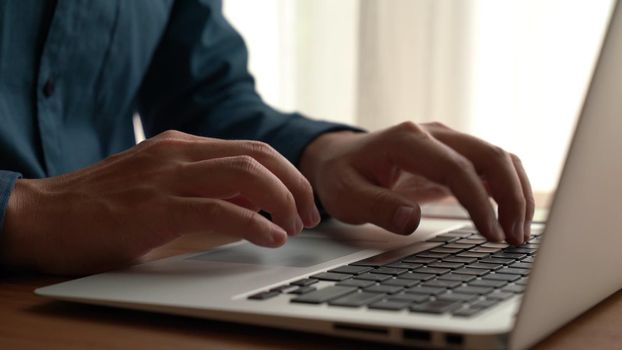 Businessman hand work on capable laptop computer at office table close up shot and selective focus at middle section of laptop computer keyboard while typing and working