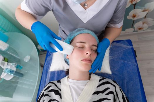 Young woman receiving electric galvanic anti-aging face spa massage at beauty salon. Galvanic massage helps to speed up metabolism, improve regeneration and restore skin protection from harmful external factors.