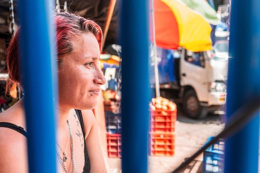 Portrait of a white Latin woman with a modern haircut with piercings on her lips and subtle tattoos in a popular market in Boaco, Nicaragua.
