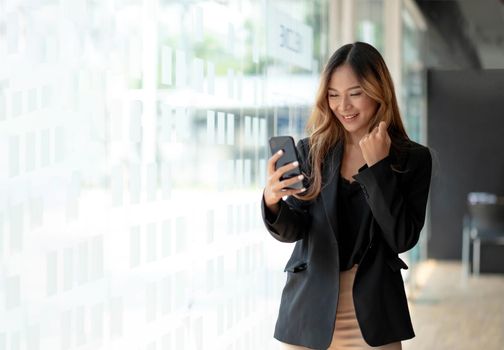 Beautiful asian woman using smartphone, exciting and celebrating with good news of business successful. Small business startup concept..