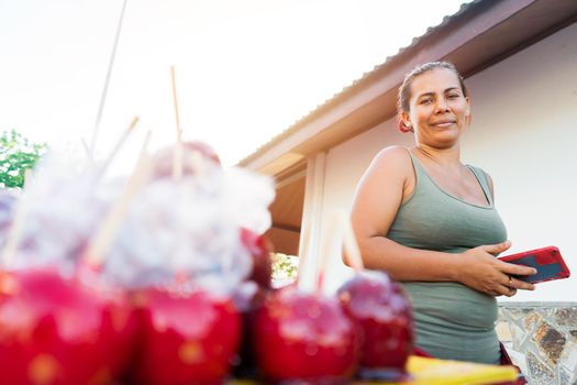Seller of caramel apples in a park in Managua, Nicaragua. Mature latin woman with green eyes smiling and looking at the camera.