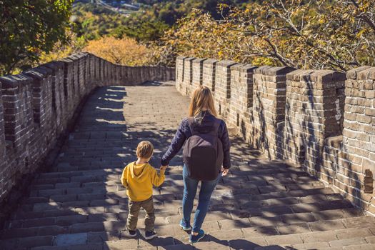 Happy cheerful joyful tourists mom and son at Great Wall of China having fun on travel smiling laughing and dancing during vacation trip in Asia. Chinese destination. Travel with children in China concept.