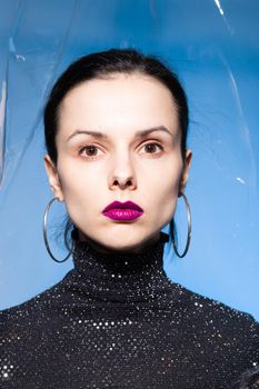 brunette woman with purple lips, blue background. High quality photo