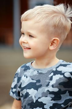 Happy boy wearing military camouflage shirts is looking at somewhere. Bristle hair and good mood