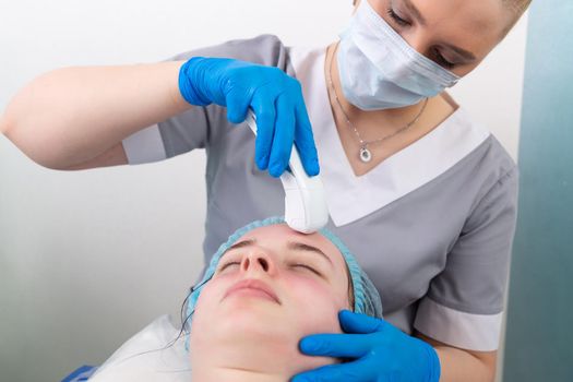 Young woman receiving electric galvanic anti-aging face spa massage at beauty salon. Galvanic massage helps to speed up metabolism, improve regeneration and restore skin protection from harmful external factors.