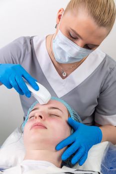 Young woman receiving electric galvanic anti-aging face spa massage at beauty salon. Galvanic massage helps to speed up metabolism, improve regeneration and restore skin protection from harmful external factors.