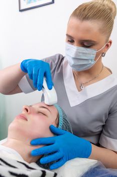 Young woman receiving electric galvanic anti-aging face spa massage at beauty salon. Galvanic massage helps to speed up metabolism, improve regeneration and restore skin protection from harmful external factors.