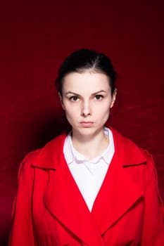 brunette woman in a white shirt red trench on a red background. High quality photo