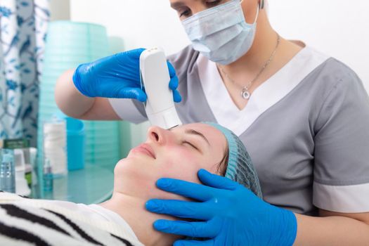 Young woman receiving electric galvanic anti-aging face spa massage at beauty salon. Galvanic massage helps to speed up metabolism, improve regeneration and restore skin protection from harmful external factors.