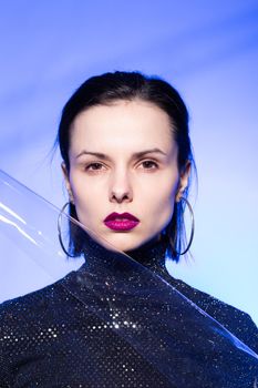 woman with purple lips in a black turtleneck with sequins on a blue background. High quality photo