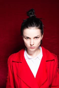 brunette woman in a white shirt red trench on a red background. High quality photo