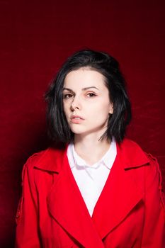 brunette woman in a white shirt red trench on a red background. High quality photo