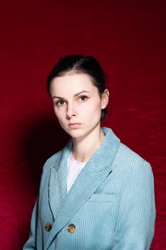 woman in white T-shirt and velvet blue jacket, red background. High quality photo