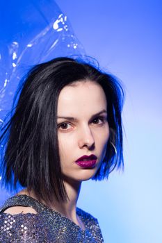 brunette woman with purple lips, blue background. High quality photo