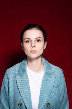 woman in white T-shirt and velvet blue jacket, red background. High quality photo