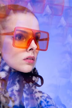 Art portrait, a woman with pink lips in orange glasses and a leopard hoodie on a blue background. High quality photo