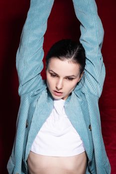 woman in white T-shirt and velvet blue jacket, red background. High quality photo