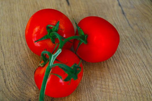 There is a branch of red tomatoes on the table. Healthy healthy food