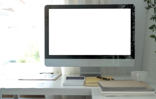 Blank screen desktop computer in minimal office room with decorations and copy space.