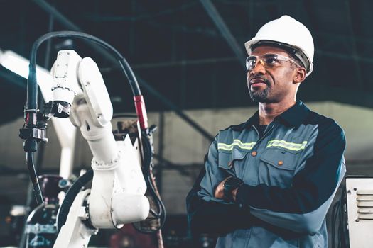 African American factory worker working with adept robotic arm in a workshop . Industry robot programming software for automated manufacturing technology .