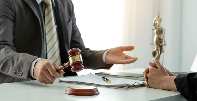 Business and lawyers discussing contract papers with brass scale on desk in office. Law, legal services, advice, justice and law concept picture with film grain effect.