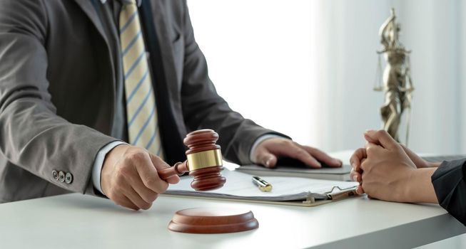 Business and lawyers discussing contract papers with brass scale on desk in office. Law, legal services, advice, justice and law concept picture with film grain effect.