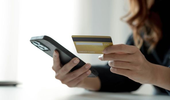 Asian woman checking online order details on smartphone Close control of credit card information entered..